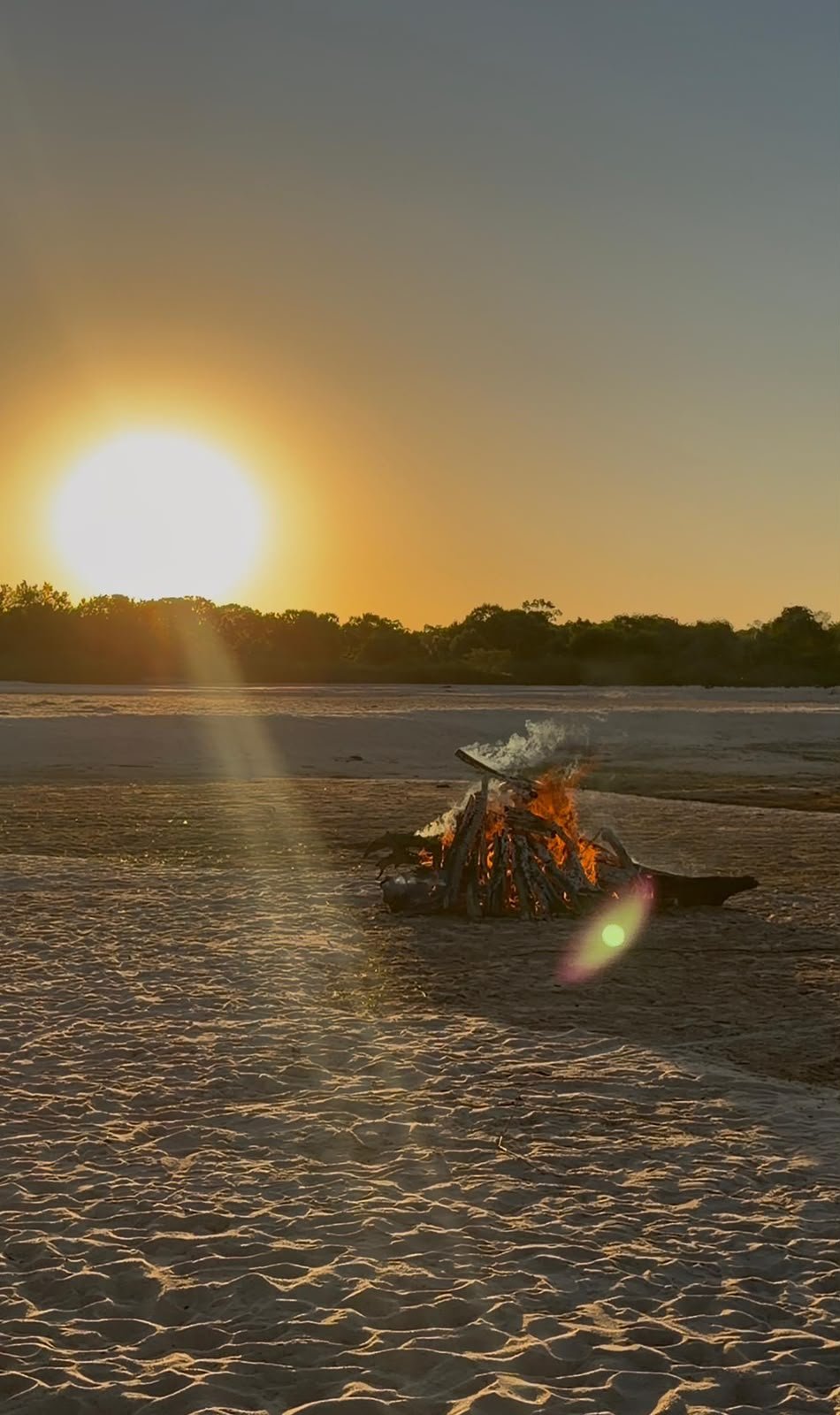 Fogueira acesa na praia ao pôr do sol