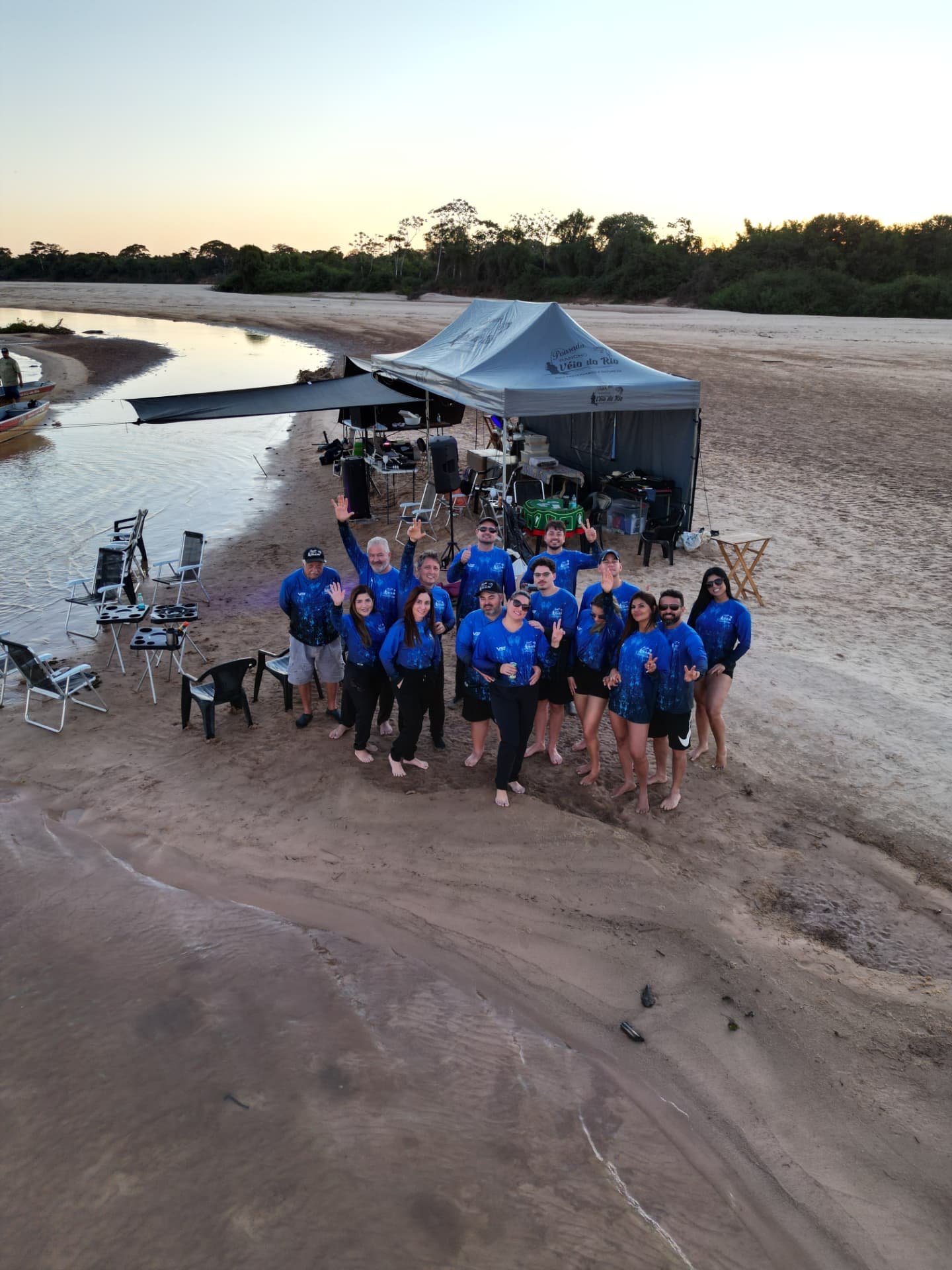 Grupo sob a barraca da pousada na praia ao pôr do sol