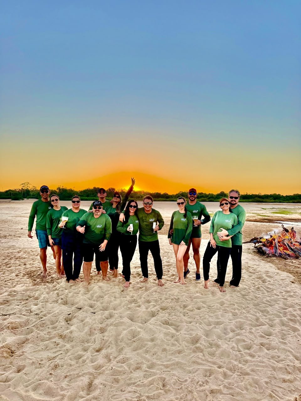 Turma de hóspedes na praia com fogueira ao fundo